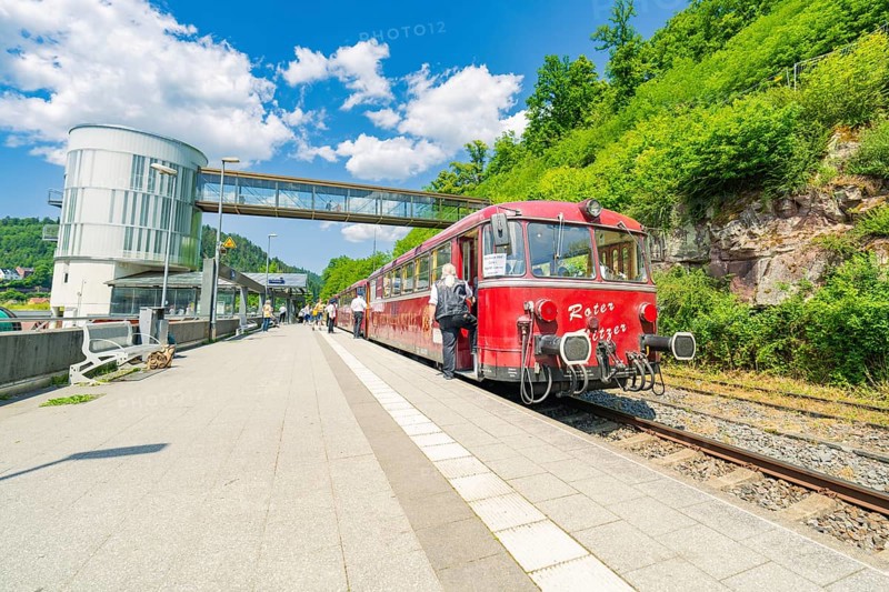 Red train stands on the platform in bright daylight, Calw railway station festival, Black Forest, Germany