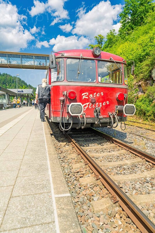 Travellers boarding a red train in the sunshine, Calw station festival, Black Forest, Germany