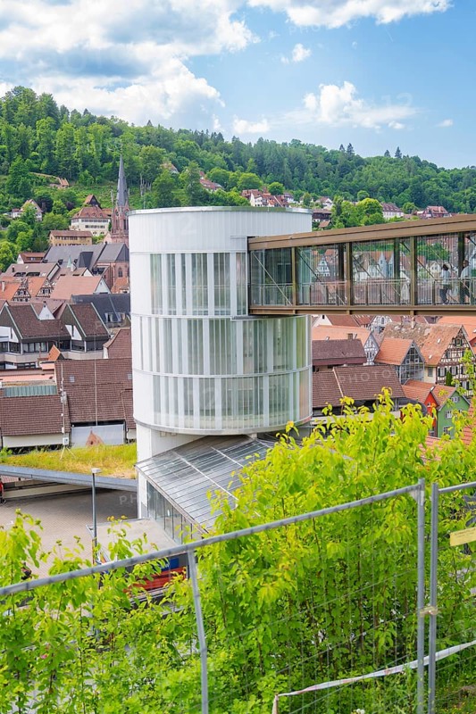 A modern building with a bridge in a town surrounded by green landscape and houses, Zob extension with bridge construction for the new Herman Hesse railway, Calw, Black Forest, Germany
