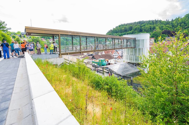 People standing on a modern bridge with city and green views, Zob extension with bridge construction for the new Herman Hesse railway, Calw, Black Forest, Germany