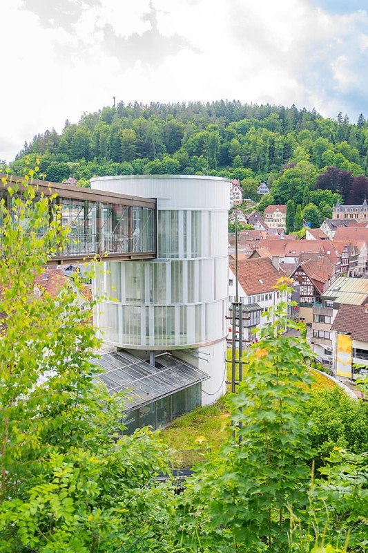 A round modern tower rises above a green, hilly urban landscape, Zob extension with bridge construction for the new Herman Hesse railway, Calw, Black Forest, Germany