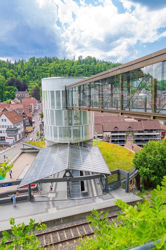 Modern pedestrian bridge over a railway station in a green, small town under a blue sky, Zob extension with bridge construction for the new Herman Hesse railway, Calw, Black Forest, Germany