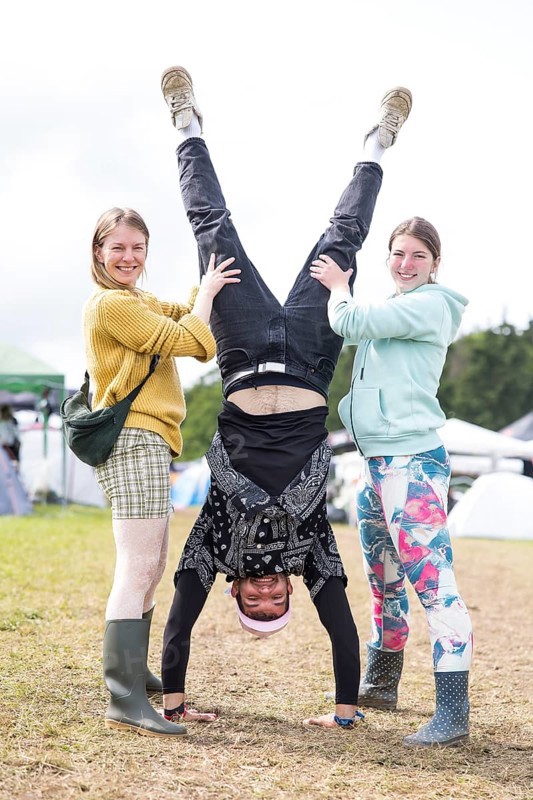 A festival visitor with a handstand thanks to the support of two woman on a camping site at the Rock am Ring Festival on Saturday, Nürburgring race track race track, 07.06.2025