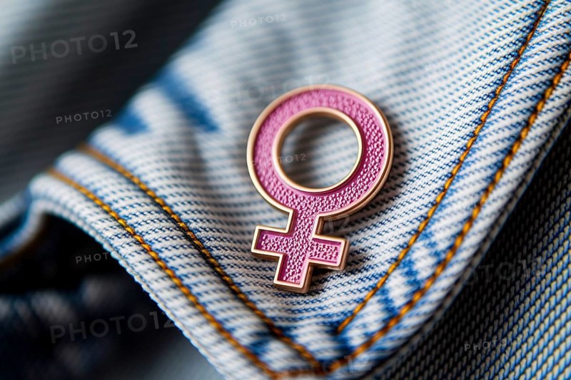 Pink female gender symbol pin attached to denim jacket, symbol of feminism and identity. Generative ai, AI generated