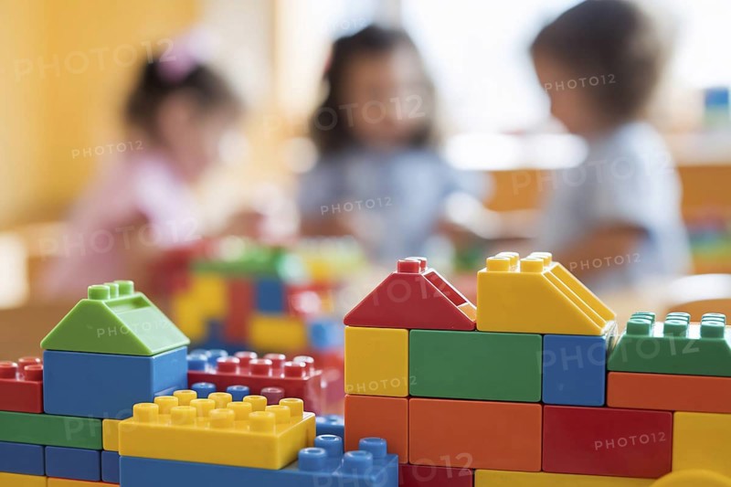Colorful building bricks in sharp focus with children playing in the background, capturing the lively atmosphere of a child daycare center. Generative AI, AI generated
