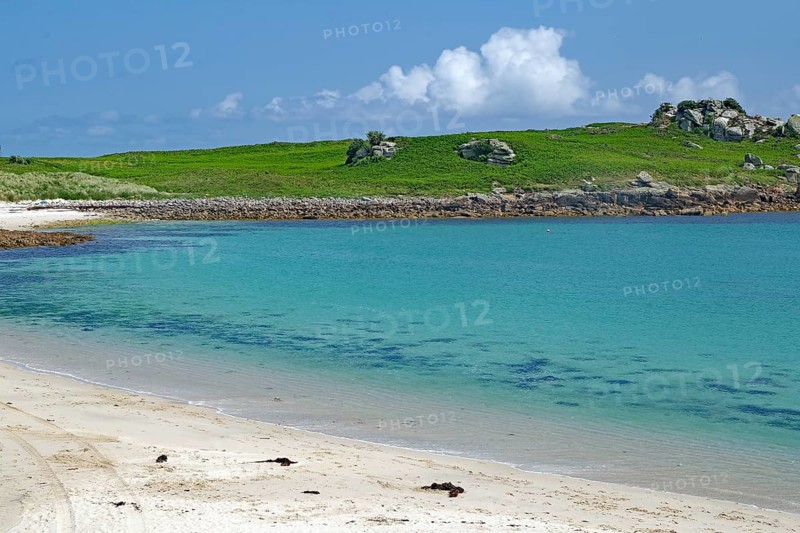 Pristine sandy beach with clear turquoise water and green hill in the background, St Agnes, Isles of Scilly, Cornwall, England, United Kingdom
