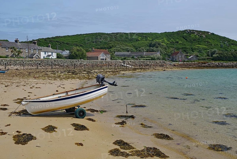 Small boat on a trailer on a quiet sandy beach near residential houses, Tresco, Isles of Scilly, Cornwall, England, United Kingdom