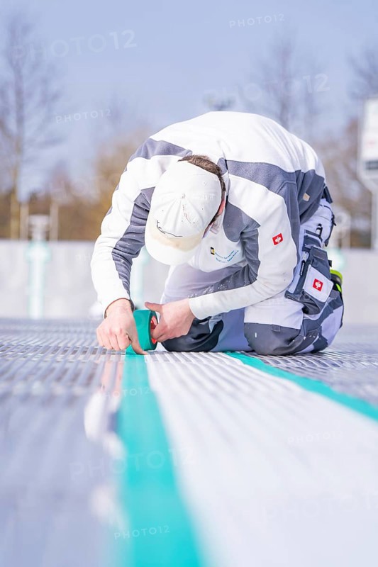 Close-up of a worker applying adhesive tape with a concentrated look on his face, renewing the swimming lines, Calw Stammheim outdoor pool, Calw, Black Forest, Germany