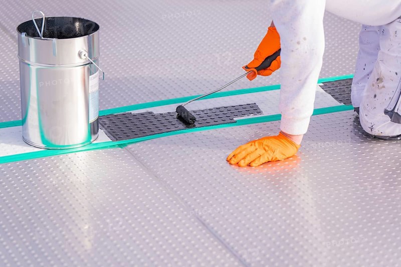 A person applies paint to the floor with a paint roller, next to it a bucket, renewal of the swimming lines, Calw Stammheim outdoor pool, Calw, Black Forest, Germany
