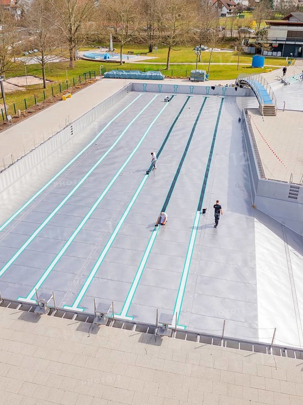People working at an empty swimming pool in a green environment, renewal of the swimming lines, Calw Stammheim outdoor pool, Calw, Black Forest, Germany