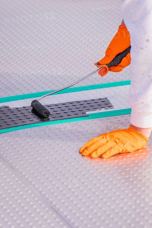 Close-up of a gloved hand using a paint roller on the floor, renovation of the swimming lines, Calw Stammheim outdoor pool, Calw, Black Forest, Germany