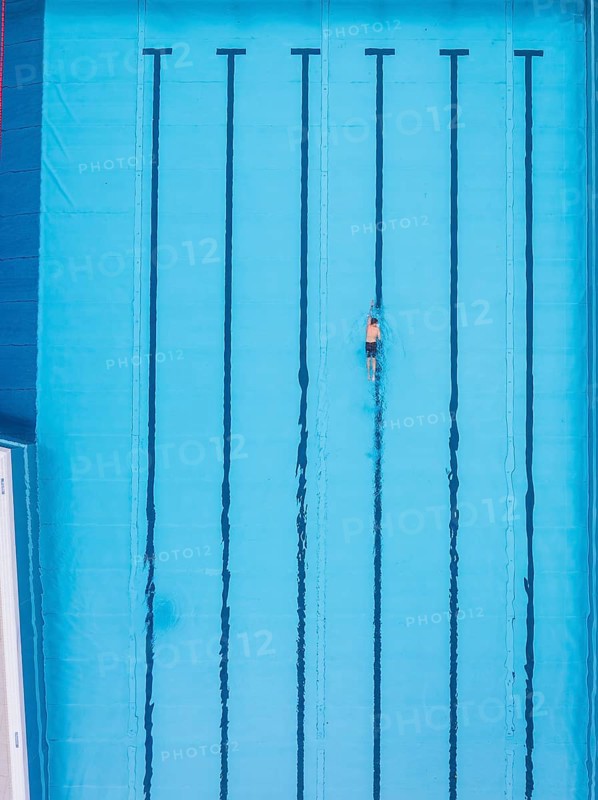 A single swimmer in an empty pool, the water is calm and clear, Calw outdoor pool, Black Forest, Germany