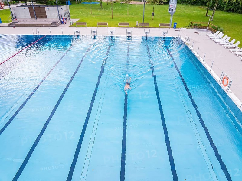 A swimmer swimming his laps in a large, empty swimming pool, Calw outdoor pool, Black Forest, Germany