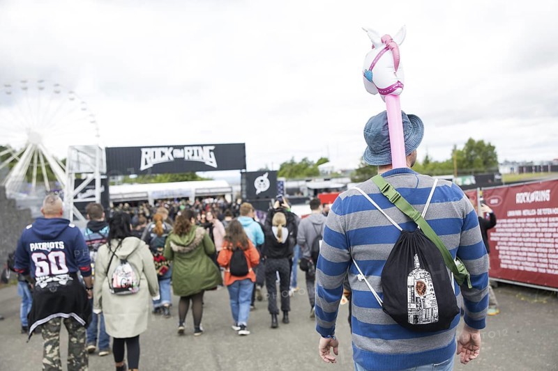 A festival visitor carries an inflatable unicorn in front of a container with the Rock am Ring logo at the Rock am Ring Festival on Friday, Nürburgring race track race track, 06/06/2025