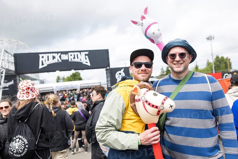Two festival visitors with their inflatable animals Charles and Chantal in front of a container with the Rock am Ring logo at the Rock am Ring Festival on Friday, Nürburgring race track race track, 06/06/2025