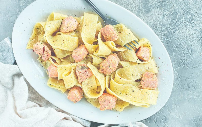 Papardelle pasta, in creamy sauce with salmon, natural light, lifestyle, homemade, on a gray background, no people