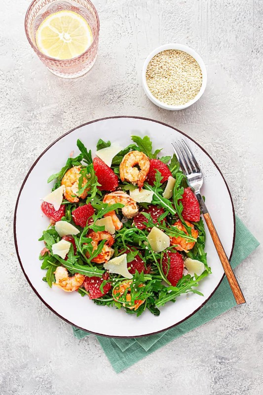 Fresh shrimp salad with arugula, grapefruit, and parmesan served in a bowl