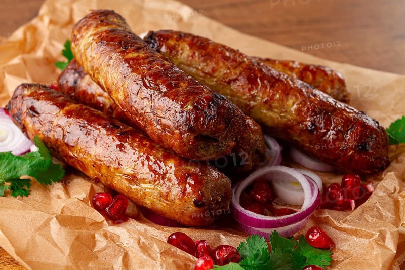 Fried kupaty on parchment, with red onion and pomegranate, kupaty, Georgian cuisine