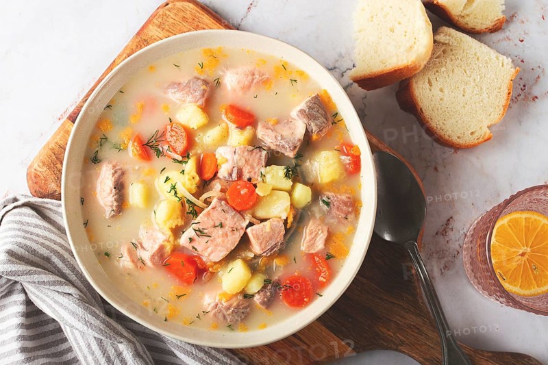 A bowl of soup on a light background, Finnish fish soup, lohikeito soup, creamy fish soup