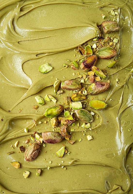 The texture of pistachio paste, with pistachios and crumbs, full frame, close-up