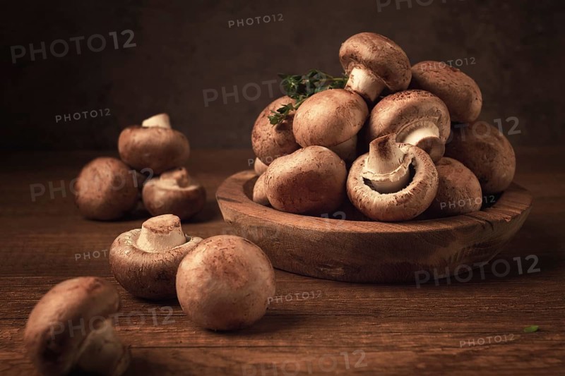 Brown champignons, royal mushrooms, in a wooden bowl, on a wooden table