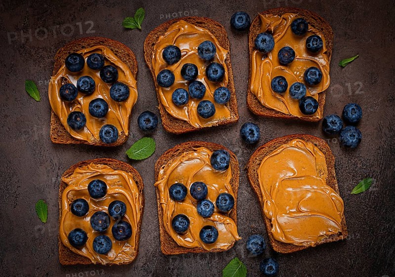 Rye bread with peanut paste and fresh blueberries, top view, no people