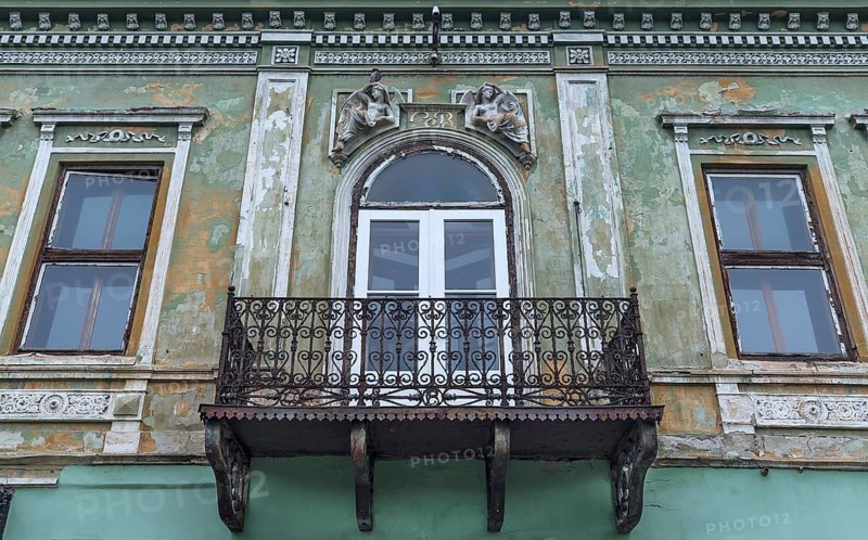 Dilapidated 19th century house with sculptures above the rusty balcony, Medias, Romania