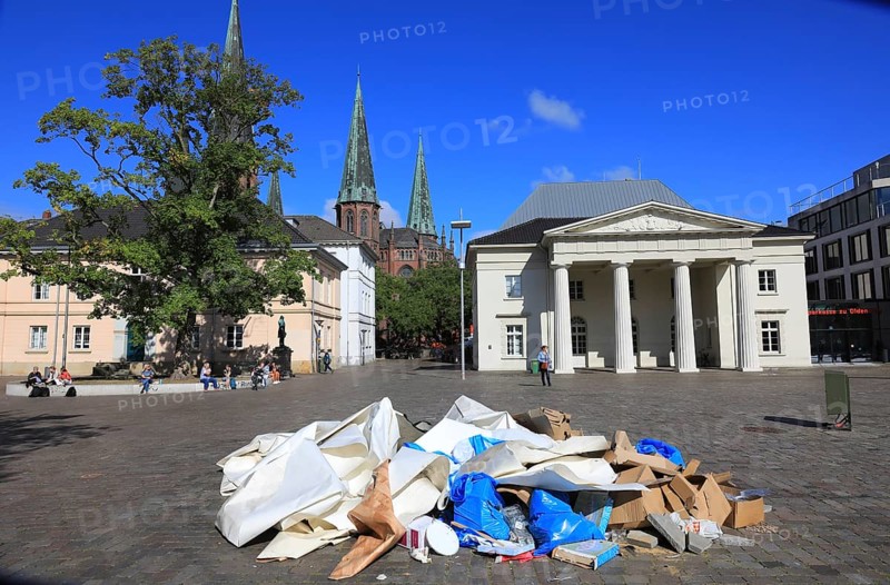 Schlossplatz with castle guard and St. Lambert's Church in the background, in the foreground a heap of waste paper, trash, remnants of an event, Oldenburg, Lower Saxony, Germany