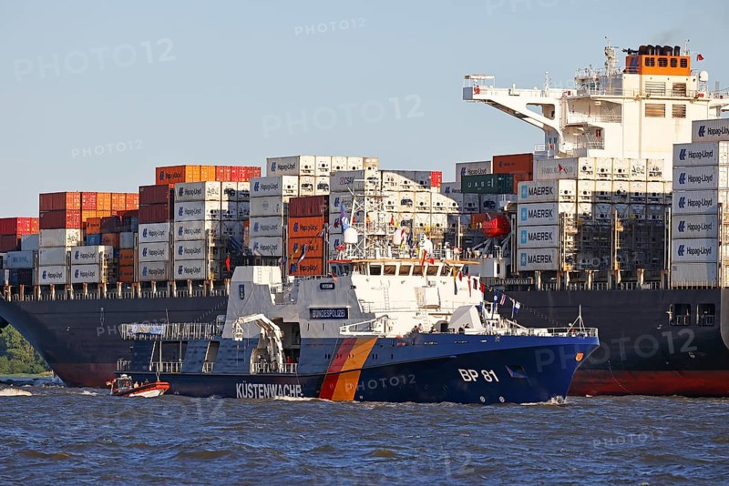 Decorated ship of the German Coast Guard and Federal Police BP 81 Potsdam leaves the Port of Hamburg on the Elbe after Hamburg's port birthday, behind it container ship sails up the Elbe towards the Port of Hamburg, shipping on the Elbe, Wedel, Schleswig-Holstein, Germany