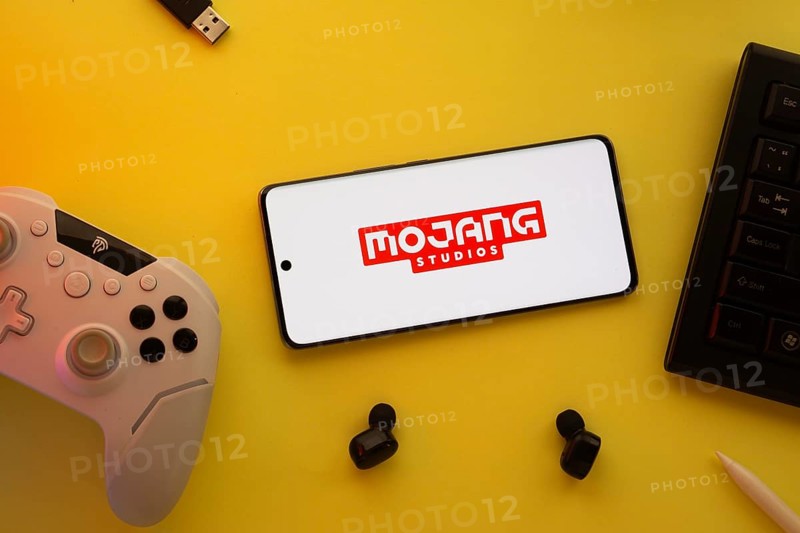 Dhaka, Bangladesh- 23 March 2025: Mojang Studios logo displayed on a smartphone surrounded by gaming accessories in an yellow light