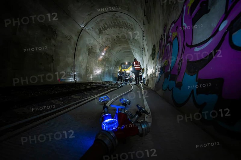 People work in the dark tunnel. Technical equipment and colorful graffiti on the walls, fire department exercise on the Hermann Hesse railway, Ostelsheim, Germany