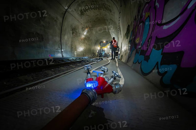 A fire hose in the foreground of a tunnel sprayed with graffiti, fire department exercise on the Hermann Hesse railway, Ostelsheim, Germany