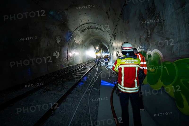 Firefighters work with hoses in a tunnel with graffiti, fire department exercise on the Hermann Hesse railway, Ostelsheim, Germany