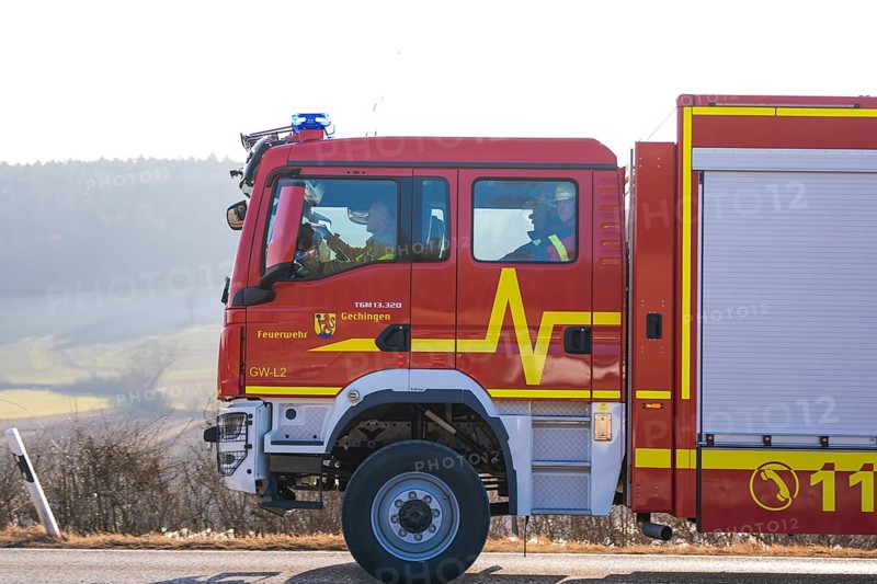 Side view of a red emergency vehicle on a wintry country road, fire department exercise on the Hermann Hesse railway, Ostelsheim, Germany