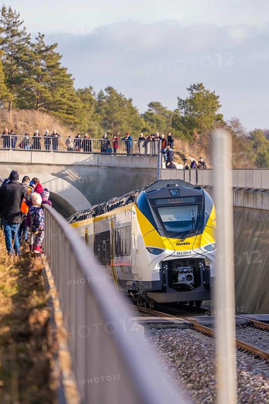Yellow train goes under a bridge. People watch from the side of the tracks. Forest in the background, fire department exercise on the Hermann Hesse railway, Ostelsheim, Germany