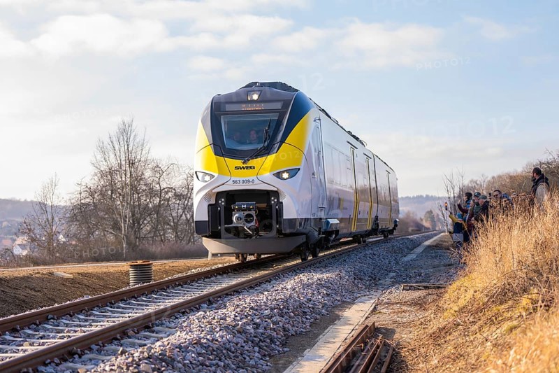 Modern train travels on tracks through rural winter landscape under clear skies, fire brigade exercise on the Hermann Hesse Railway, Ostelsheim, Germany