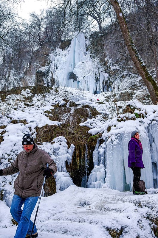 Hikers climb on the Urach waterfall full of bizarre ice formations, frozen at low winter temperatures, Bad Urach, Swabian Alb, Baden-Württemberg, Germany, for editorial use only