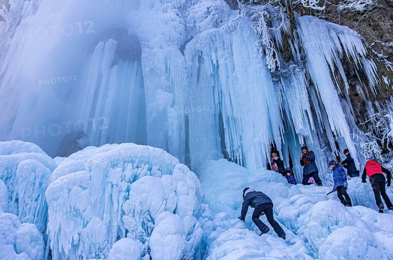 Spectators climb on the Urach waterfall full of bizarre ice formations, frozen at low winter temperatures, Bad Urach, Swabian Alb, Baden-Württemberg, Germany, for editorial use only