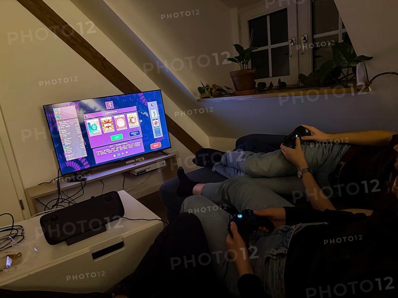 Friends sitting on the couch playing a video game on a TV with Steam Deck, video game Vampire Survivors, Munich, Bavaria, Germany