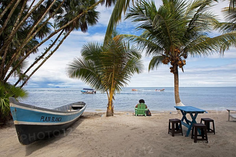 Sandy beach beach, coconut trees and boat at Playa Blanca, Izabal Department, Guatemala
