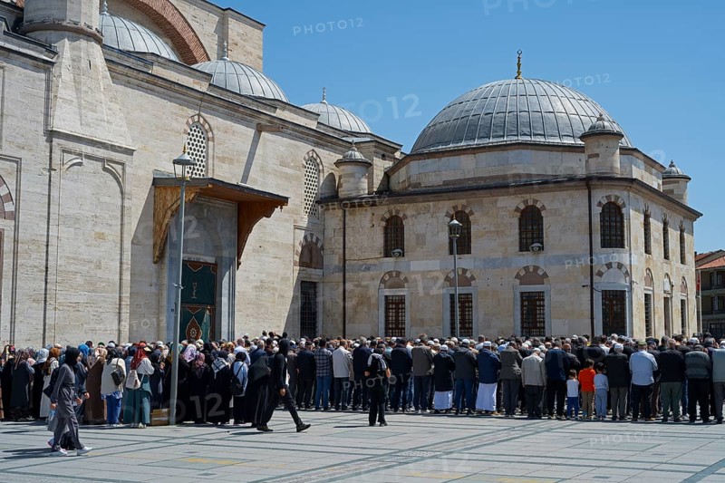 People gather in front of a large stone building with domes on a sunny day, prayer in front of the mosque, Konya Sultan Selim Camii, Konya, Central Anatolia, Turkey