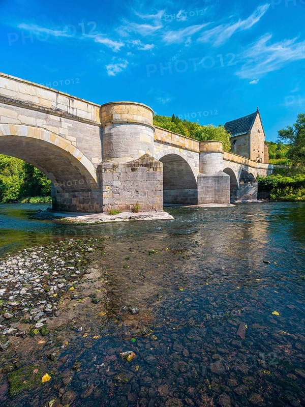 13th century medieval stone bridge across the Werra river, in the back the Liborius chapel, Creuzburg, Thuringia, Germany