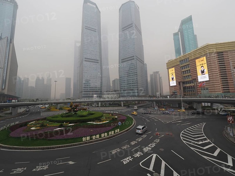 City scene with roundabout and skyscrapers in fog under grey sky, Pudong, Shanghai, China
