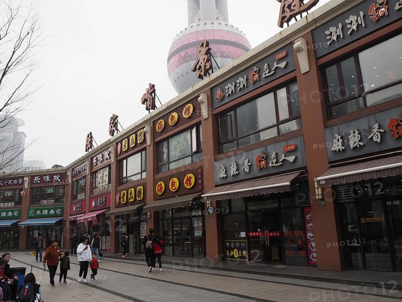 Commercial street with people and view of the TV tower on a cloudy day, Pudong, Shanghai, China