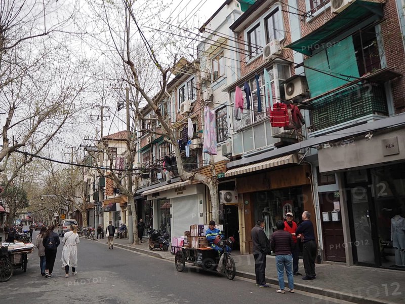 Street scene with pedestrians and residential buildings reflecting everyday life in a lively city, French Concession, Shanghai, China