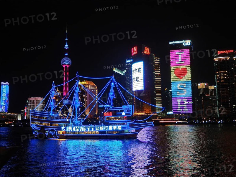 Illuminated skyline and river with an illuminated ship at night, Shanghai, China