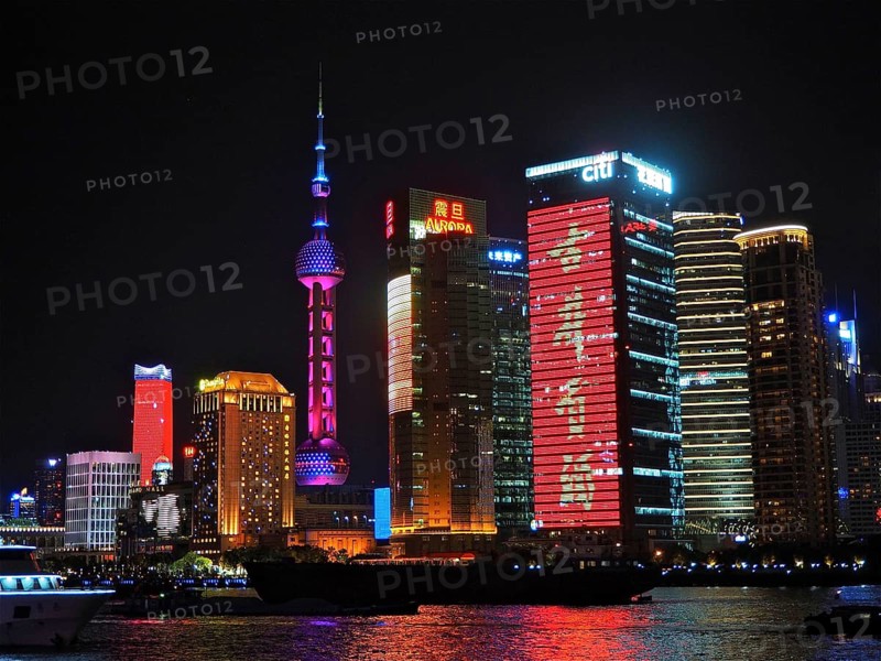 Illuminated skyscrapers and neon signs at night on a riverbank, Shanghai, China