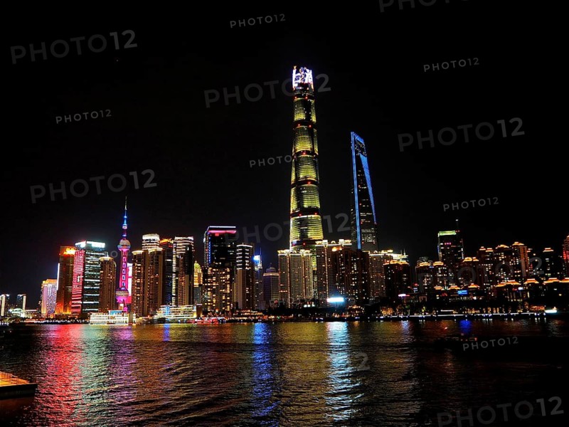 Impressive skyline of high-rise buildings, illuminated at night, stretching behind a river, Shanghai, China