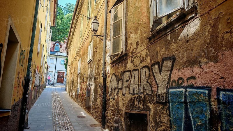 Narrow alleys with graffiti, historic facades and colorful tones dominate the picture, Ljubljana, Slovenia
