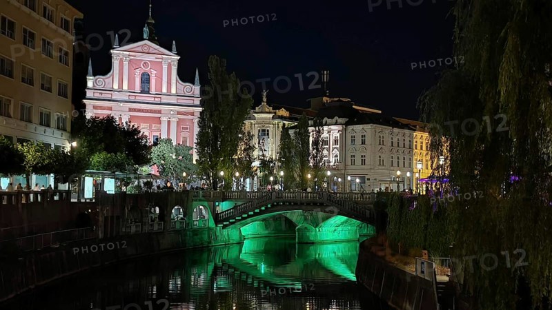 River with illuminated bridge and historic buildings in an atmospheric night view, Ljubljana, Slovenia